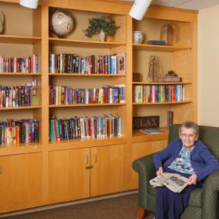 An elderly woman enjoying a book in a cozy library setting.
