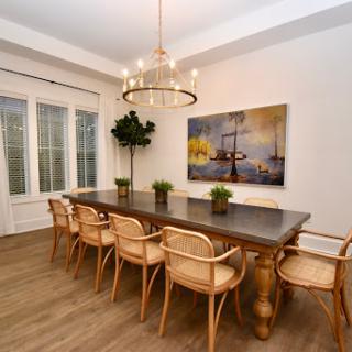 A stylish dining room featuring a large wooden table surrounded by elegant chairs and adorned with decorative plants.
