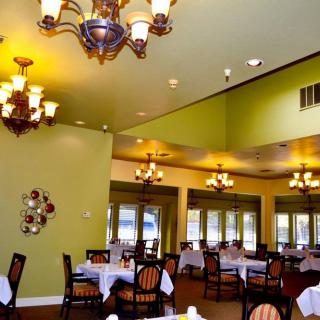 A well-lit restaurant interior with elegant chandeliers hanging above neatly arranged tables and chairs.