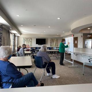 A group of adults attending a class with an instructor using a whiteboard.