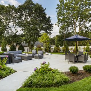 A beautifully landscaped backyard patio area with seating and umbrellas.