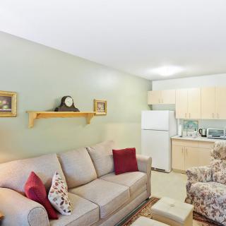A cozy living room with a sofa, cushions, and a kitchenette in the background.