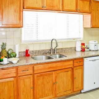 A clean and bright kitchen with wooden cabinets, a double sink, and various appliances on the countertop.