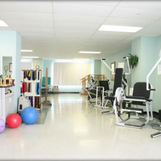 A well-equipped rehabilitation gym featuring various exercise machines and stability balls.