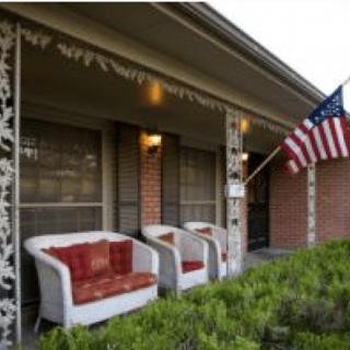 A cozy porch with chairs and an American flag in the evening light.