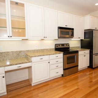 A modern kitchen with white cabinets, granite countertops, and stainless steel appliances.