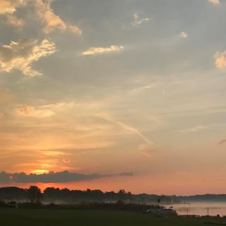 A serene sunset over a calm body of water with a picturesque sky.