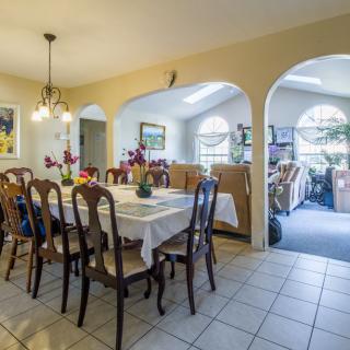 A cozy dining area with a large table and chairs, featuring arched doorways and ambient lighting.