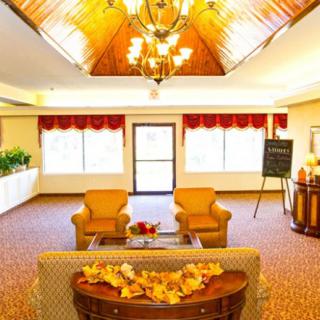 A well-lit lobby area featuring comfortable seating, warm lighting from a chandelier, and decorative elements.