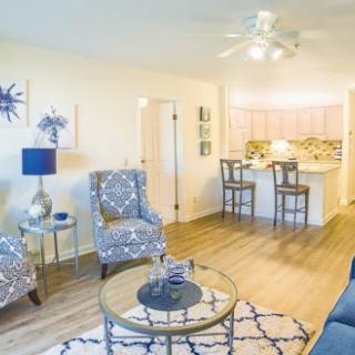 A stylish and modern living room featuring blue accents and an open-concept design that seamlessly connects to the kitchen.