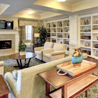 A cozy and elegantly designed living room featuring comfortable seating, a fireplace, and built-in shelves filled with decor.
