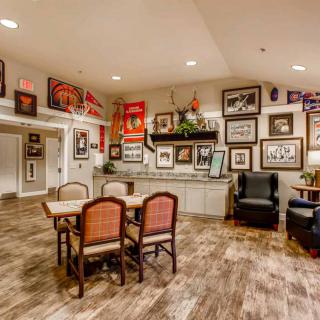 A cozy room with a gallery wall filled with various framed artworks and photos, along with comfortable seating and wooden flooring.