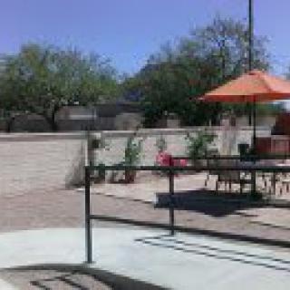 A sunny patio with seating and an orange umbrella.