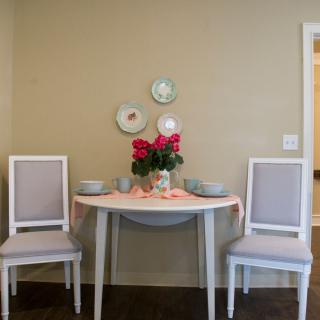 A cozy dining setup with a small table, two chairs, and decorative roses.