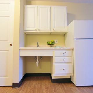 A simple kitchen setup with white cabinets, a countertop, and a fridge.
