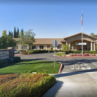 A one-story building with a flagpole in front, surrounded by landscaped greenery and a parking area.