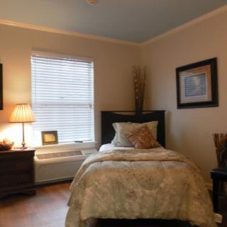 A cozy bedroom with a single bed, warm lighting, and tasteful decor.