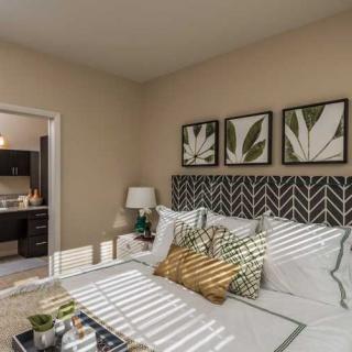 A modern bedroom with stylish decor, featuring botanical artwork and patterned pillows.