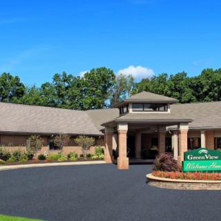 A building with a central entrance surrounded by trees and a clear blue sky.