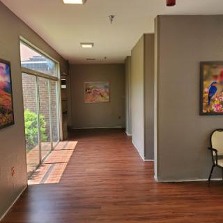 A bright and modern hallway featuring artwork on the walls and wooden flooring.