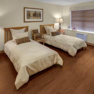 A cozy bedroom with twin beds and wooden flooring.