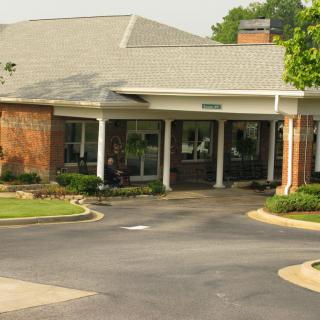 An inviting building entrance with a driveway and landscaped surroundings.