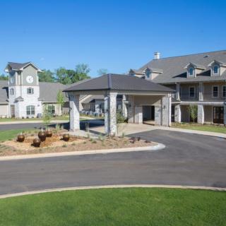 A modern residential building with a landscaped entrance and driveway.
