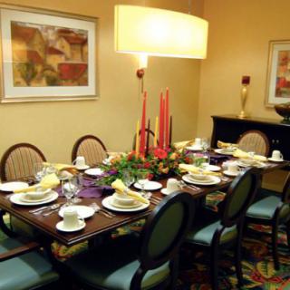 A formal dining room setup with a beautifully arranged table, complete with candles and elegant tableware.