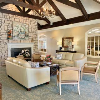 A cozy living room featuring a stone fireplace, elegant chandelier, and comfortable seating arrangements.