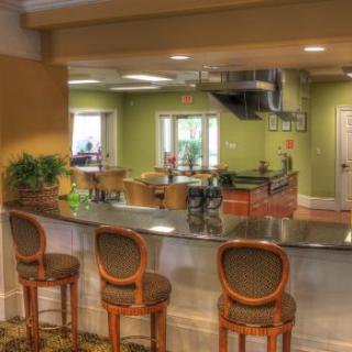A modern kitchen with a bar counter and bar stools, featuring green walls and an open layout.