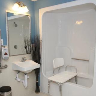 An accessible bathroom with a walk-in shower, equipped with a chair and grab bar.
