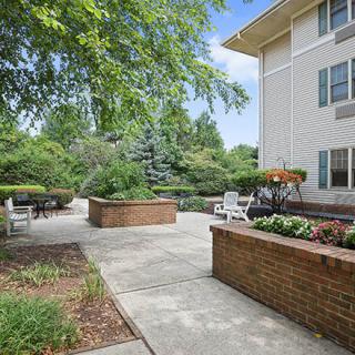 A tranquil apartment patio area with lush greenery and comfortable seating.