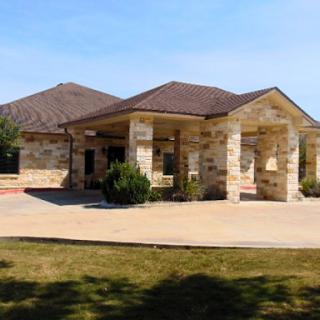 A beautiful single-story house with a stone exterior, surrounded by landscaped grounds.