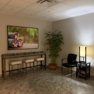 A cozy waiting room with seating, artwork, and a floor lamp.