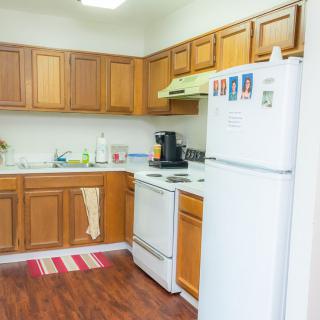 A cozy kitchen with wooden cabinets, a stove, and a refrigerator.
