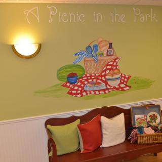 A cozy interior featuring a picnic-themed mural with a bench adorned with colorful pillows.