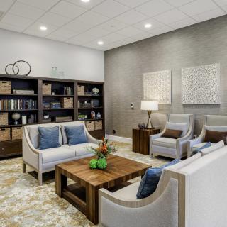 A modern living room featuring comfortable sofas, armchairs, a coffee table, and a stylish bookshelf.