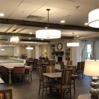 A cozy dining area with tables, chairs, and warm lighting.
