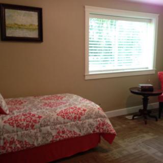A cozy bedroom with a single bed near a window, featuring a small table and chair.