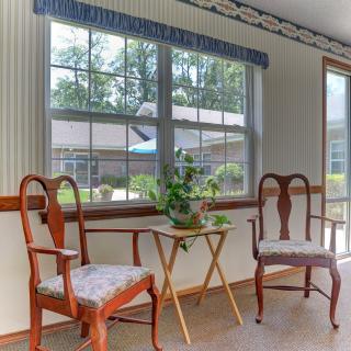 A cozy sitting area with two wooden chairs and a small table holding a plant by the window.