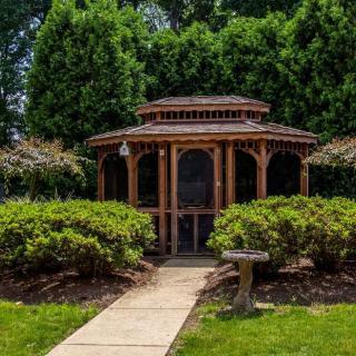 A picturesque gazebo surrounded by lush greenery and a well-maintained garden path.