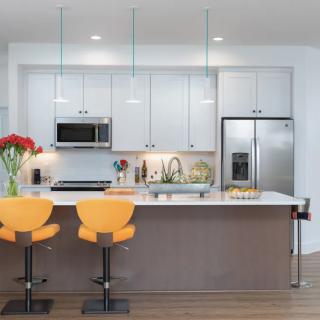 A modern kitchen with a central island and stylish stools.