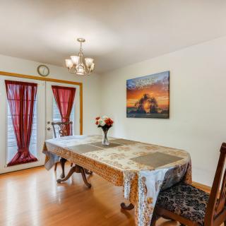 A cozy dining room with a table set for two, adorned with a floral arrangement and an elegant chandelier overhead.