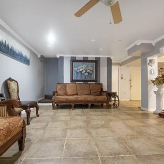 A spacious living room with a sofa, armchair, and tile flooring.