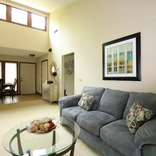 A modern living room featuring a cozy gray sofa, a stylish coffee table, and artwork on the walls, illuminated by natural light.