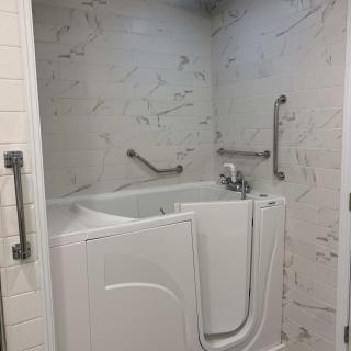 A bathroom featuring a walk-in tub with accessibility grab bars.