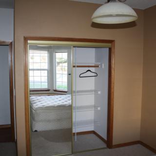 A bedroom with a mirrored closet door and a window.