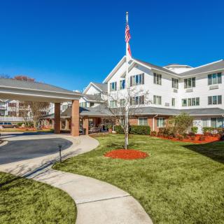 A scenic view of a senior living community with manicured lawns and an American flag.