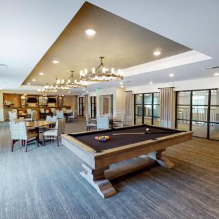 A modern game room featuring a billiard table and elegant seating area with chandeliers.