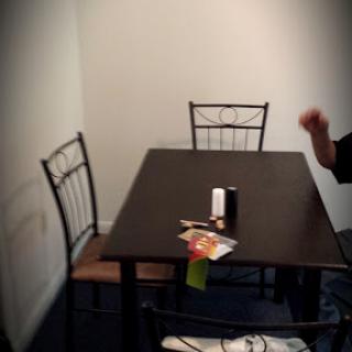 A simple dining area with a table and two chairs, featuring some items placed on the table.